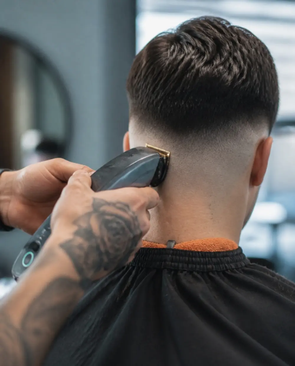 Barber trimming a skin fade on the back of a client’s head with clippers